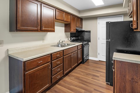 A kitchen with wooden cabinets and a black refrigerator.
