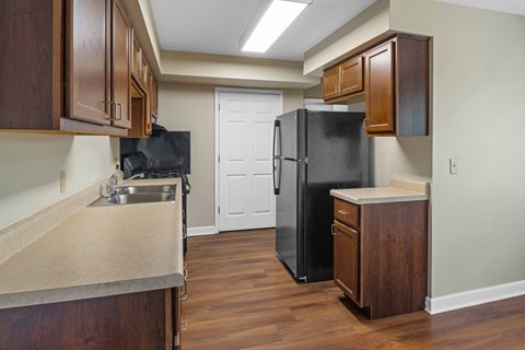 A kitchen with a black fridge and wooden cabinets.