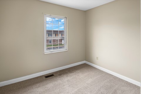 A room with a window showing a view of a building outside.