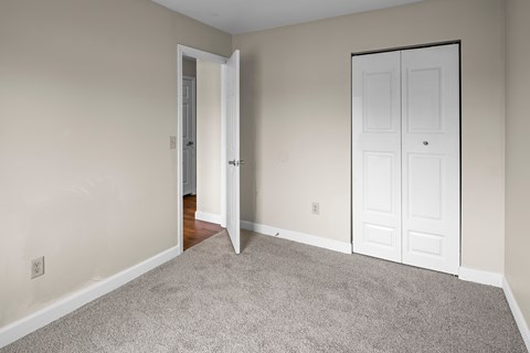 A room with a carpeted floor and a white door.