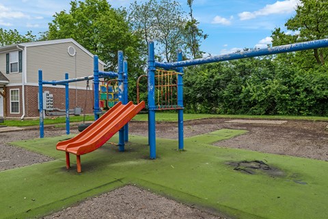 A playground with a red slide and a blue monkey bar.