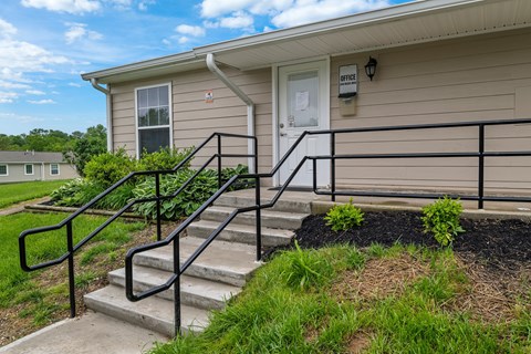 A beige house with a black railing on the stairs.