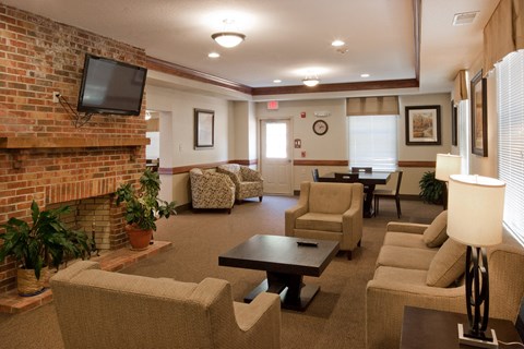 A living room with a brick fireplace and a flat screen TV mounted above it.
