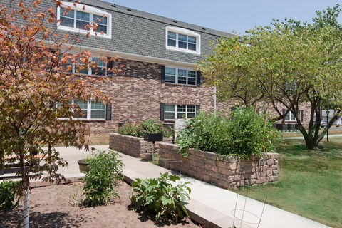 A building with a grey roof and a stone wall in front of it.