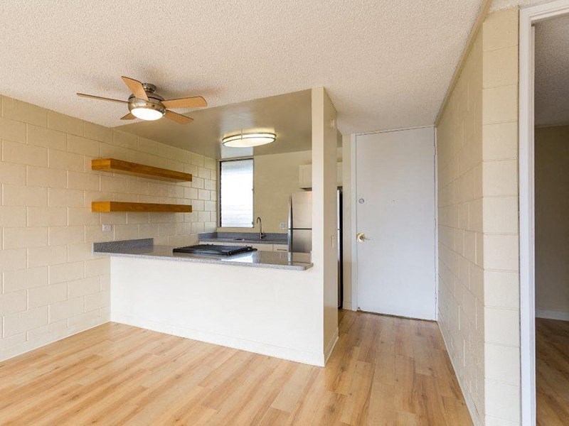 an empty room with a kitchen and a ceiling fan at Palms of Kilani Apartments, Hawaii