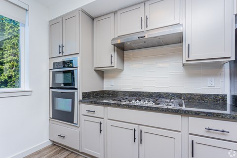A kitchen with white cabinets and a granite countertop.