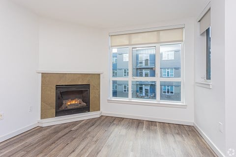 A room with a fireplace and a window showing a building outside.
