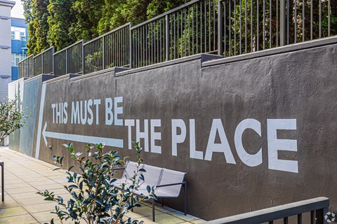 A wall with the words "This must be the place" painted on it.