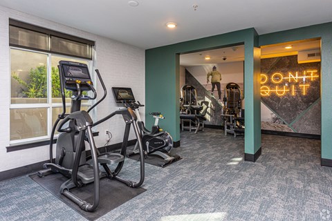 A gym with a neon sign that says "Don't Quit" in the background.
