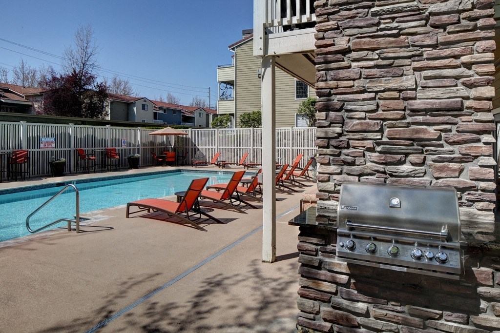 a swimming pool with chairs and a grill on the side of the resident clubhouse at 2000 Lake Washington Apartments, Renton, WA