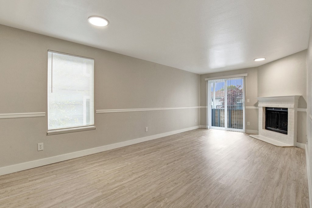 an empty living room with a fireplace and a sliding glass door at 2000 Lake Washington Apartments, Renton, WA