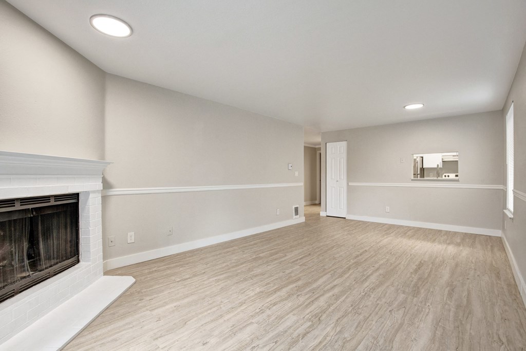 an empty living room with a fireplace and wood flooring at 2000 Lake Washington Apartments, Washington