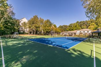 a tennis court with trees and a house in the background at Deerfield Village, Alpharetta, Georgia