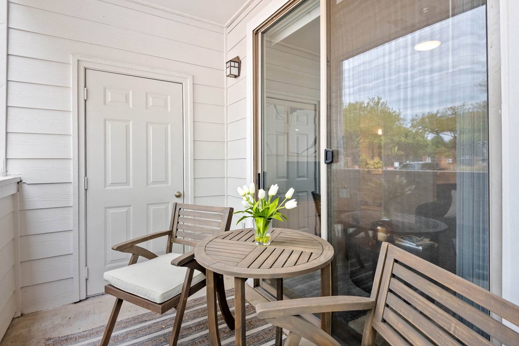a small porch with a table and chairs and a sliding glass door at Mission Gate, Texas, 75024