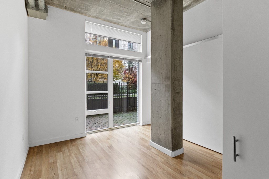 a living room with a large window and a door to a balcony at The Parker Apartments, Portland