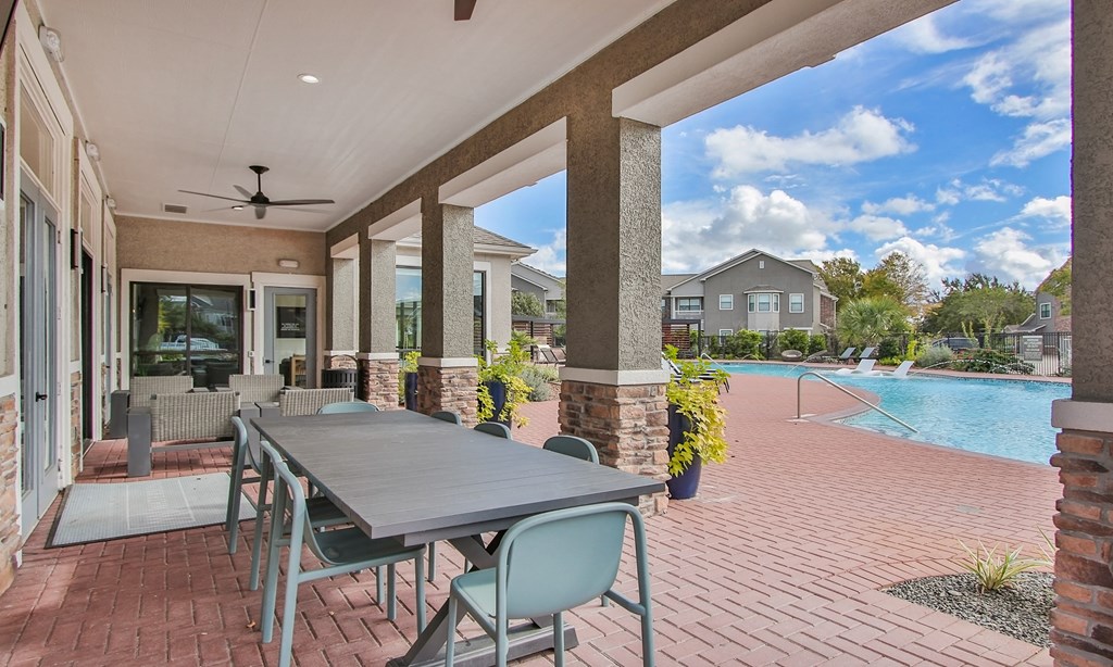 an outdoor patio with a table and chairs and a swimming pool at Sladestone Shadow Creek, Pearland, TX