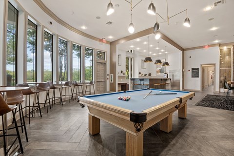 a pool table in the clubhouse of a community with tables and chairs at Mission Gate, Plano