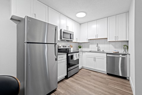 an apartment kitchen with stainless steel appliances and white cabinets