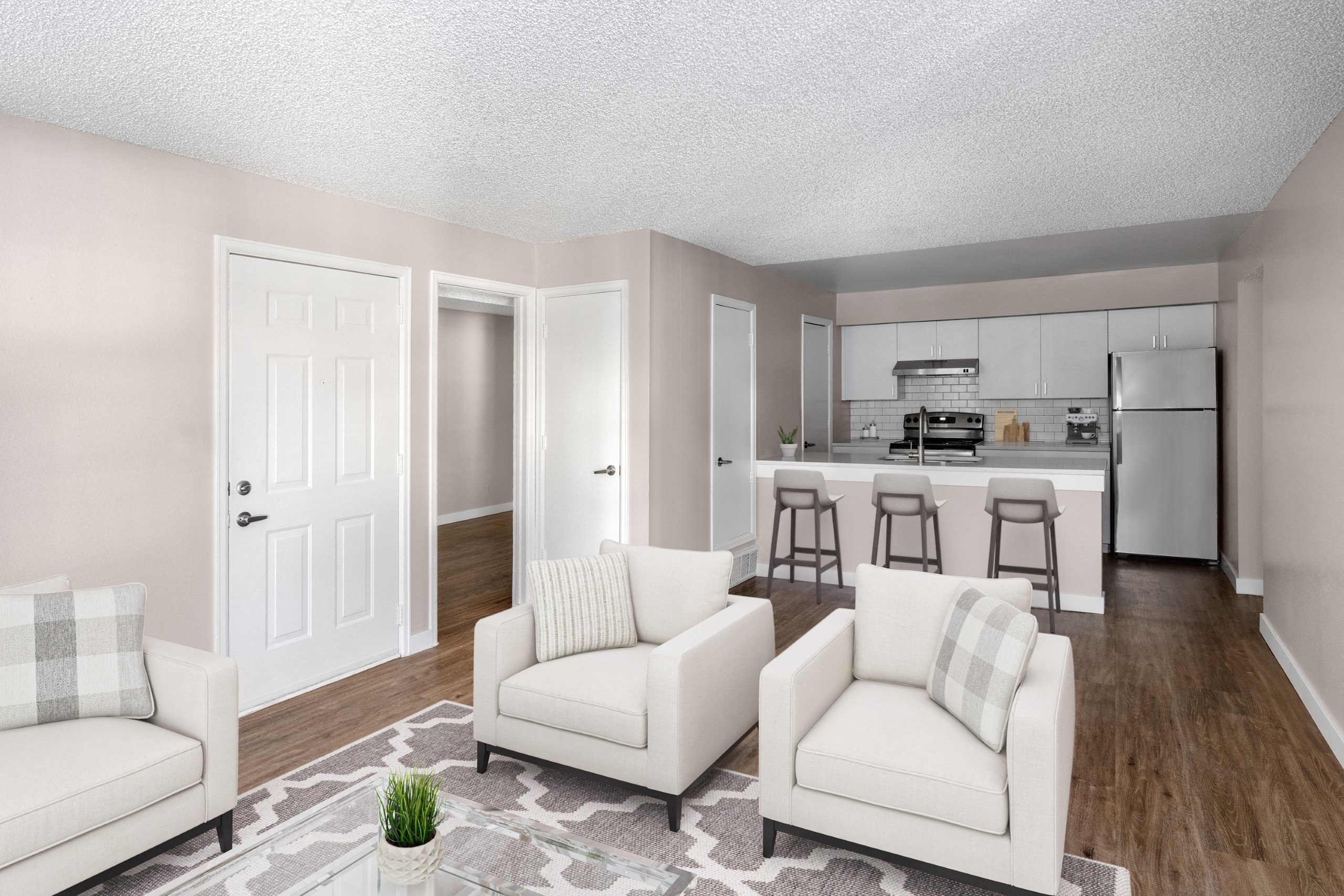 the living room and kitchen of a model home with white couches and chairs