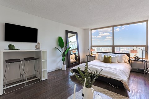 a bedroom with a large bed and a large window and a desk with a tv at Presidential Towers in Illinois 60661