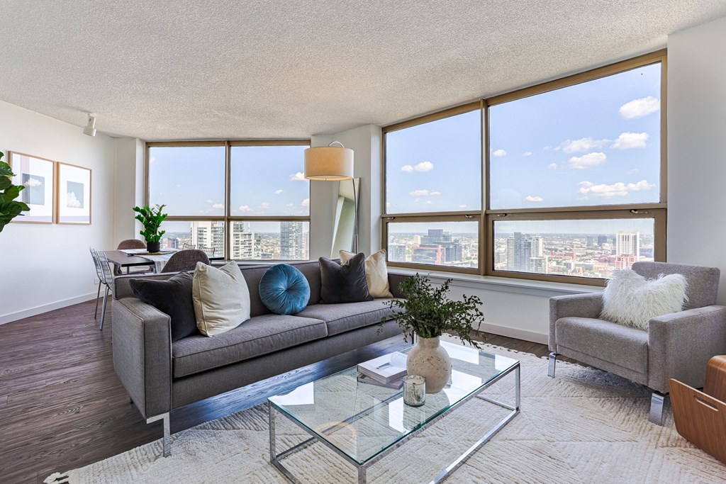a living room with a couch and a glass coffee table and large windows