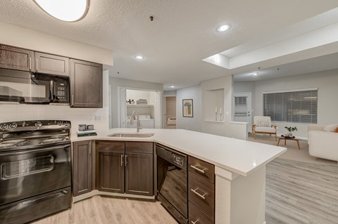 A modern kitchen with dark brown cabinets and a white countertop.