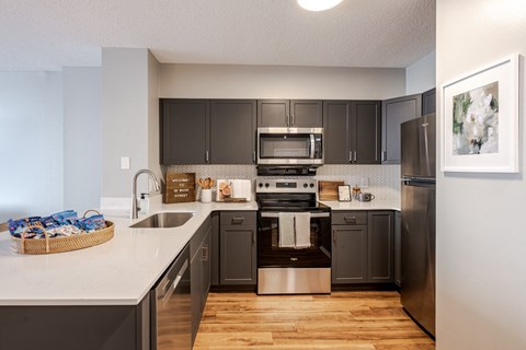 A modern kitchen with dark brown cabinets and stainless steel appliances.