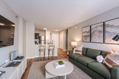 A living room with a green couch, a white coffee table, and a painting on the wall.