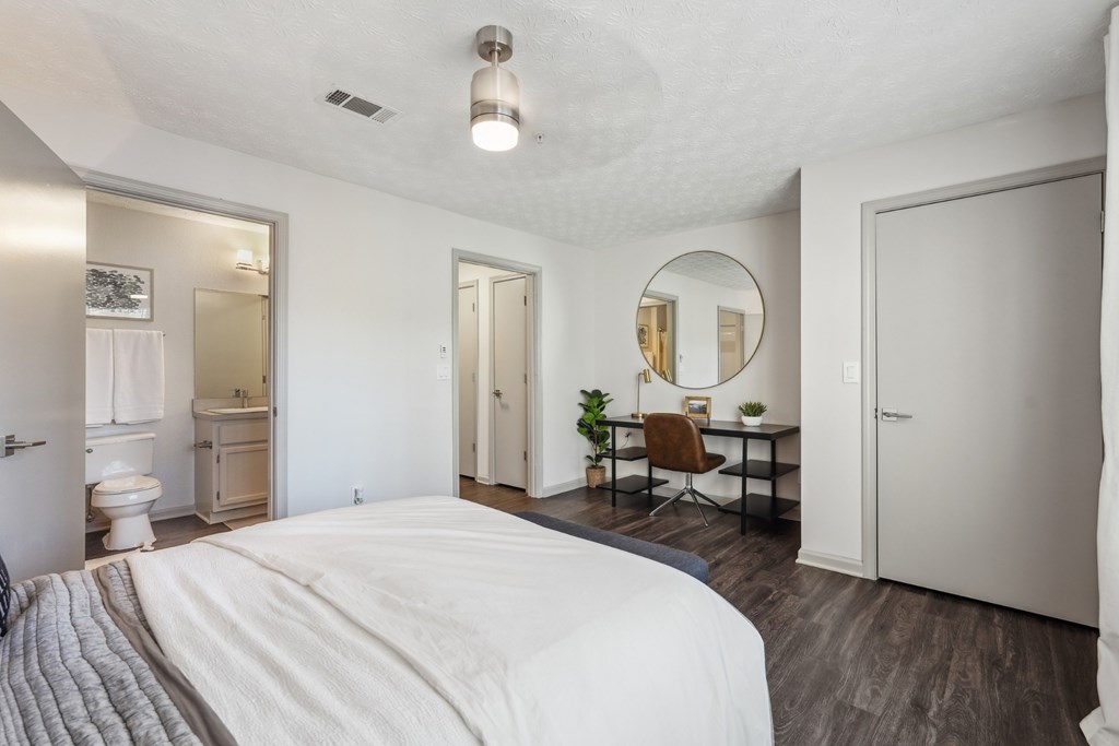 A bedroom with a large bed and a desk with a chair.