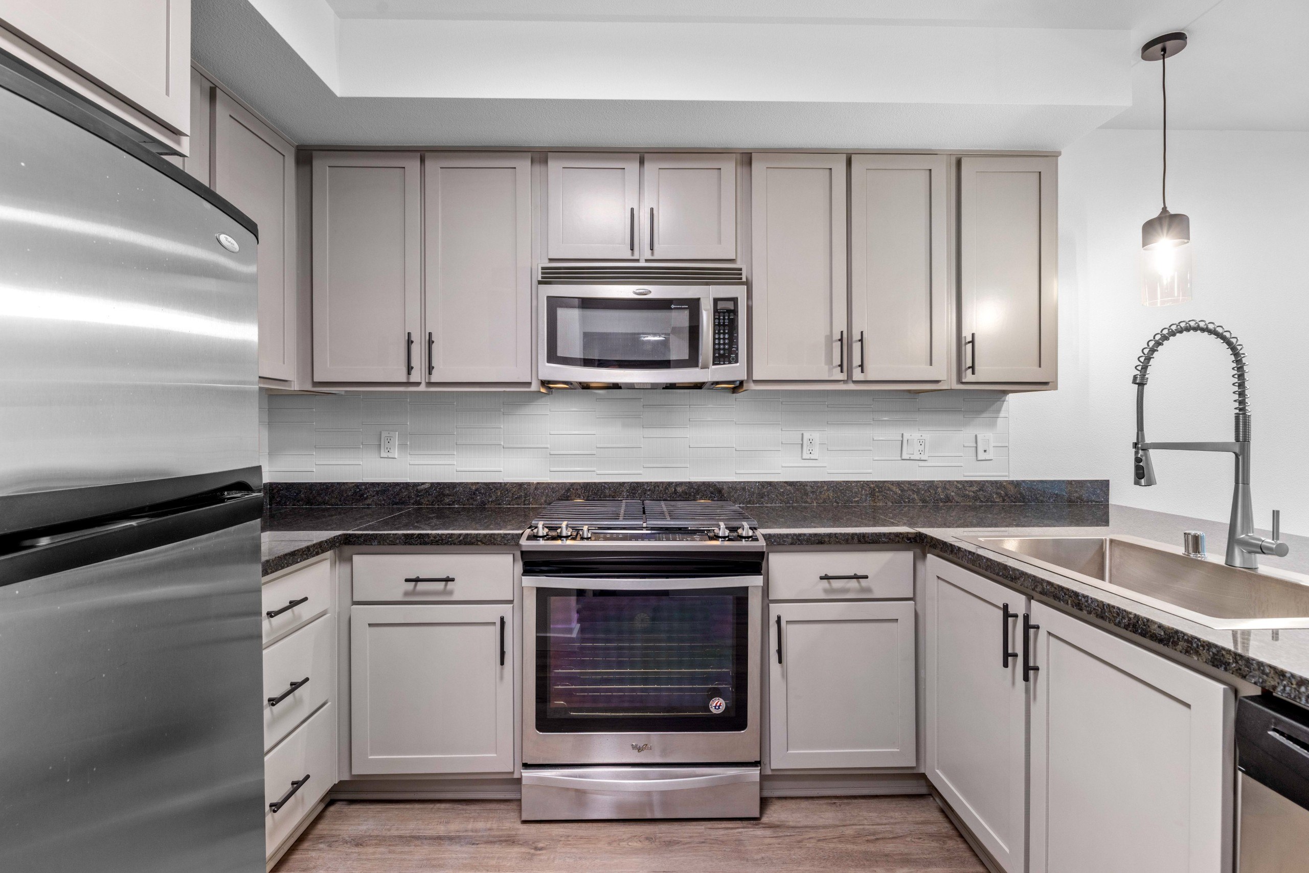 A modern kitchen with a stainless steel refrigerator and a microwave above the stove.