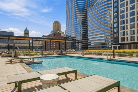 A pool surrounded by benches and a city skyline in the background.