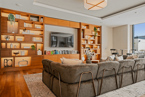 A living room with a large couch and a television on a wooden wall.