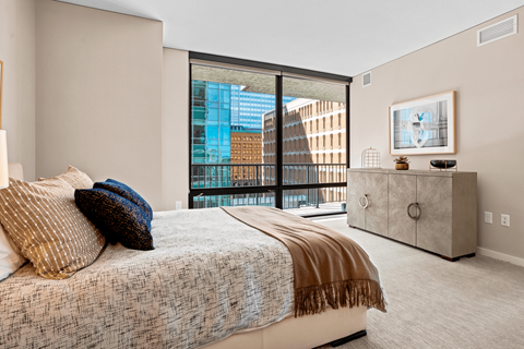 A bedroom with a large bed and a balcony overlooking a city.