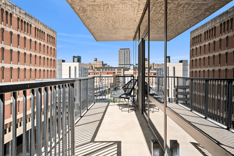 A balcony with a table and chairs overlooks a cityscape.