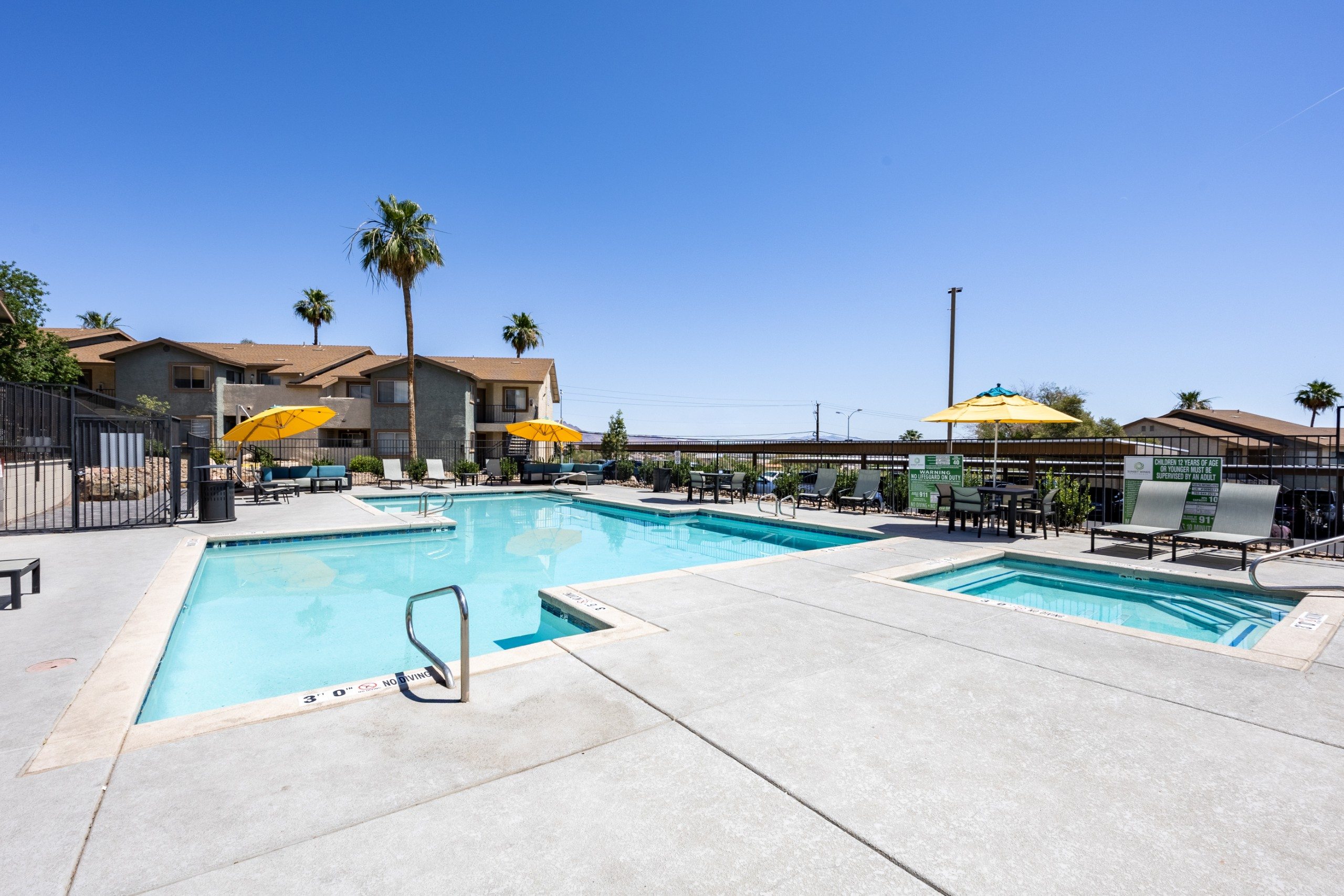 A swimming pool with a yellow umbrella and a palm tree in the background.