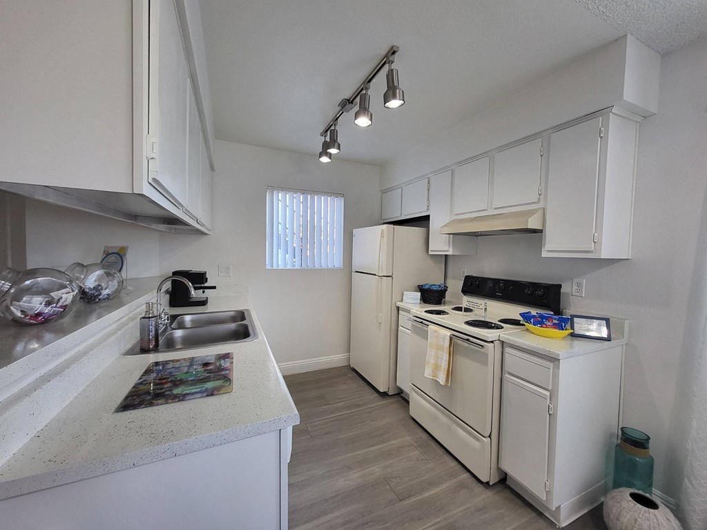 a kitchen with white appliances and white cabinets at Sunset Winds Apartments in Nevada 89014