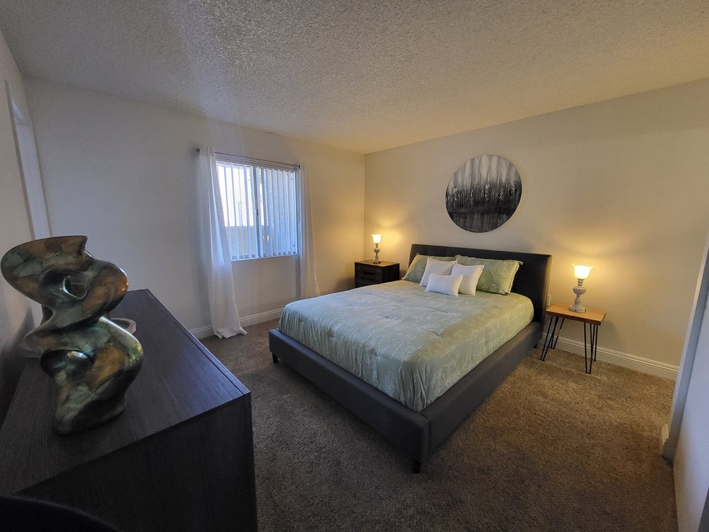 a bedroom with a bed and a dresser and a window at Sunset Winds Apartments in Henderson, 89014