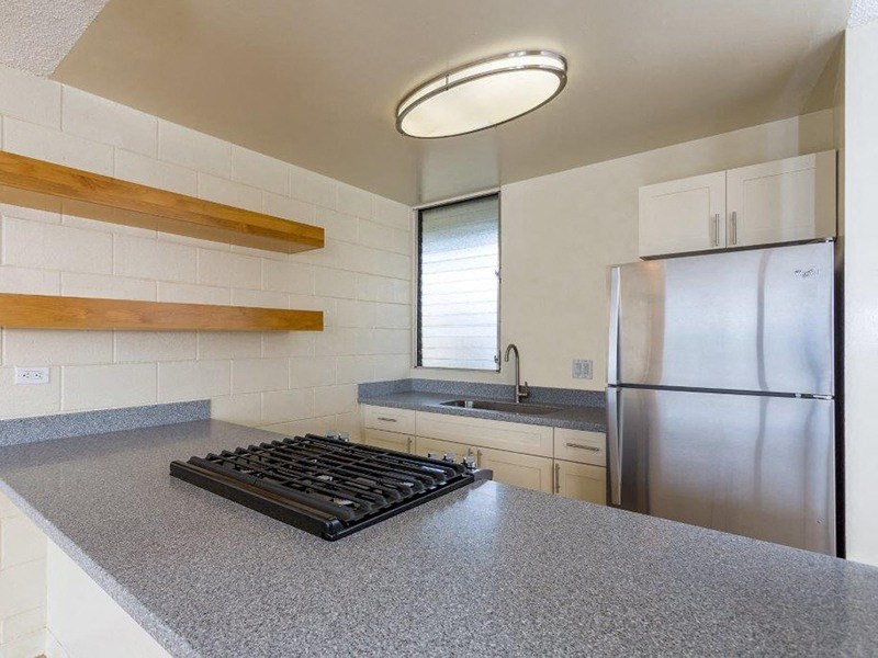a kitchen with a stove and a stainless steel refrigerator at Palms of Kilani Apartments, Wahiawa, Hawaii