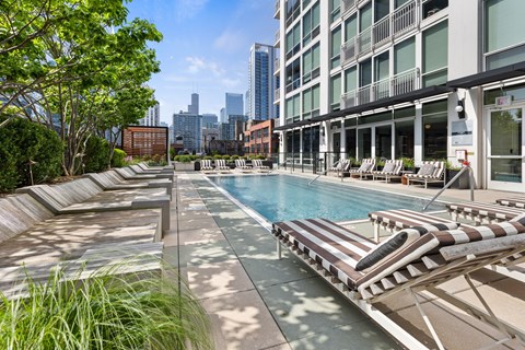 A pool area with sun loungers and a view of the city skyline.