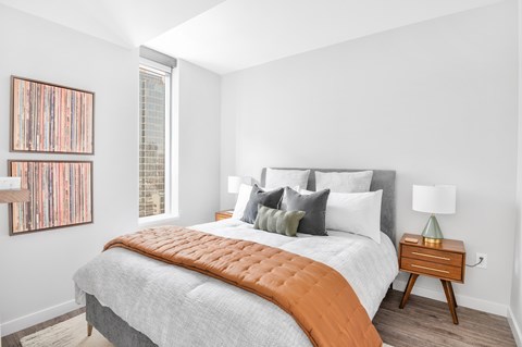 A bedroom with a bed, nightstand, and a picture on the wall.