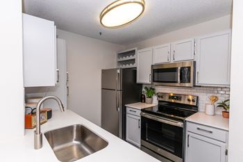 an open kitchen with stainless steel appliances and white cabinets at Briarcliff Apartments, Atlanta, 30329