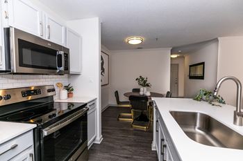 an open kitchen and dining room with white cabinets and black appliances at Briarcliff Apartments, Georgia, 30329