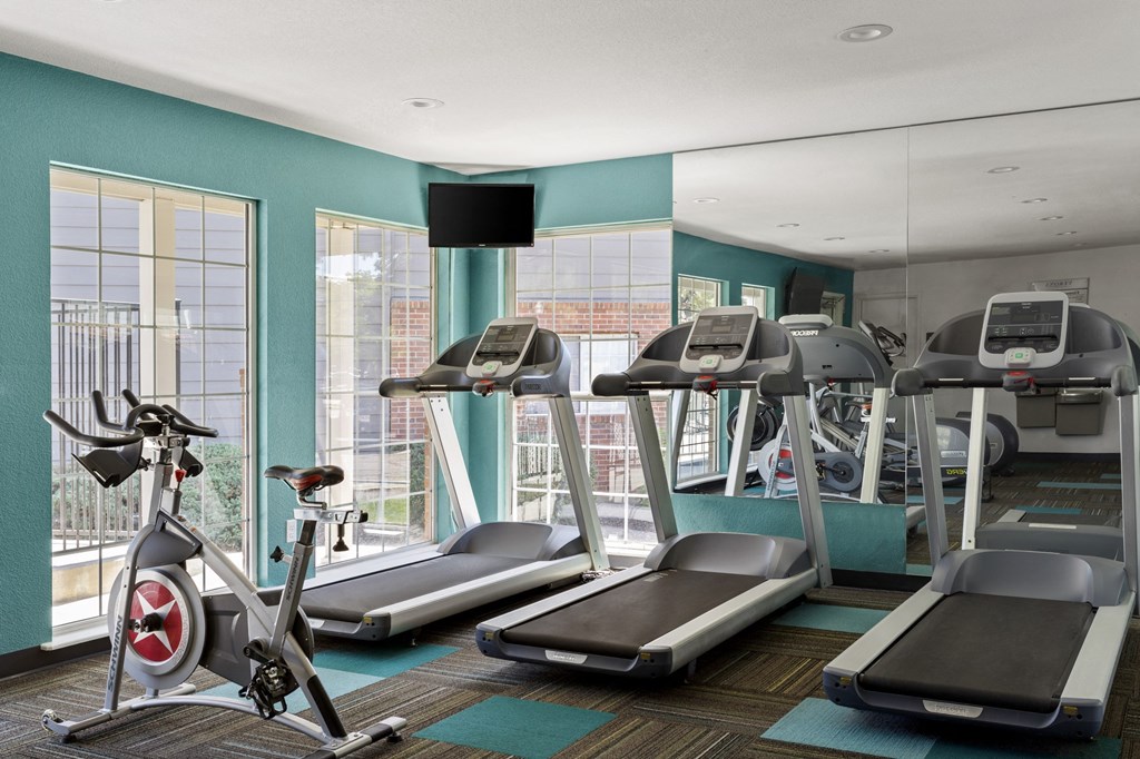 a gym with treadmills and exercise bikes in a room with windows  at Verona, Littleton, CO, 80123