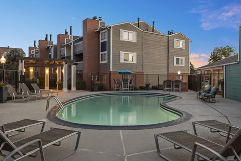 a swimming pool with chairs and a building in the background  at Verona, Colorado, 80123
