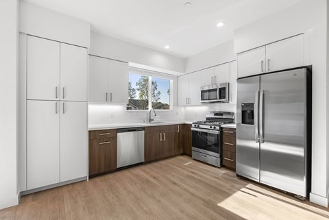 A modern kitchen with stainless steel appliances and wooden floors.
