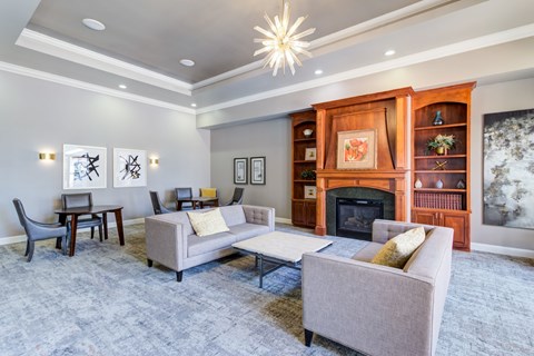 A living room with a grey couch, a chair, a table, a fireplace, and a painting on the wall.