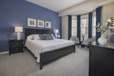 A bedroom with a large bed and a nightstand with a lamp.