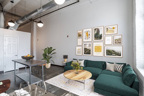 a modern living room with a green couch, a coffee table, and pictures on the wall at Highland Mill Lofts in Charlotte, NC  28204
