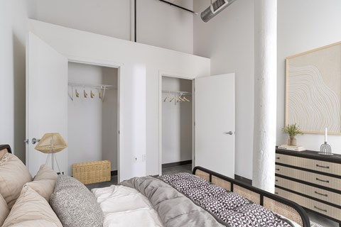 The Mill House floor plan with a white bedroom with a large bed and a wardrobe at Highland Mill Lofts in Charlotte, North Carolina 28205