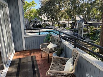 a balcony with two wicker chairs and a swimming pool